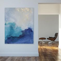 an abstract painting hangs on the wall next to a chair in a room with hard wood flooring