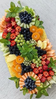 an arrangement of fruits and vegetables arranged in the shape of a triangle on a table