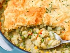 a pot filled with chicken pot pie on top of a blue plate and a spoon in it