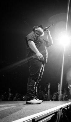 a man standing on top of a stage while holding a microphone in his hand,