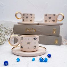 two coffee cups and saucers sitting next to each other on top of three books