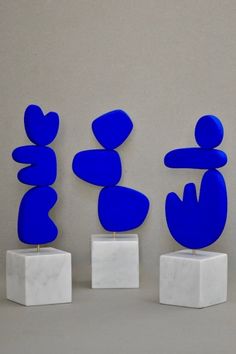 three blue sculptures sitting on top of white blocks