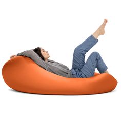 a woman laying on an orange bean bag chair with her feet up in the air