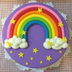 a rainbow cake with stars and clouds on it