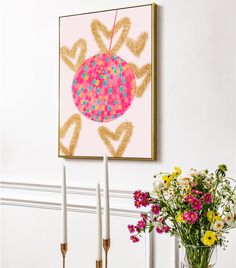 a vase filled with flowers sitting on top of a table next to two white candles