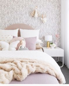 a white bed topped with lots of pillows next to a night stand and nightstands