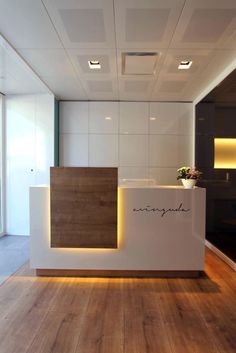 an office reception area with wood flooring and white walls, along with lights on the ceiling