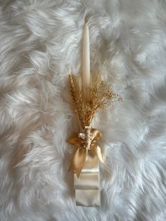 a vase with some flowers and a candle on top of a white fur covered surface