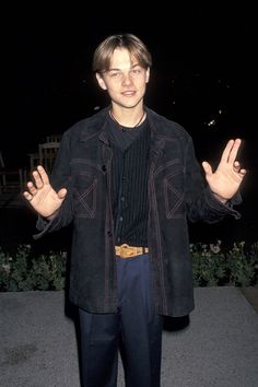 a young man standing in front of a building holding his hands out to the side