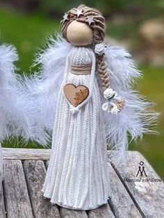 a white angel doll holding a heart on top of a wooden table