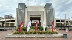 the entrance to an arena with flags and banners in front of it on a cloudy day