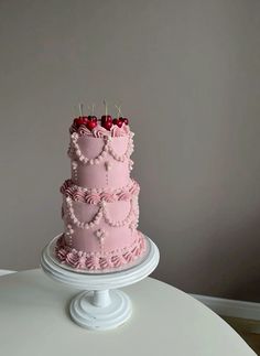 a three tiered pink cake with cherries on top