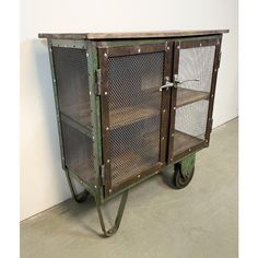 an old metal cart with mesh doors and wheels on the floor next to a wall