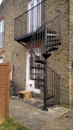 a black spiral staircase next to a brick building