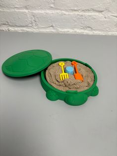 a green sand box filled with toys on top of a table