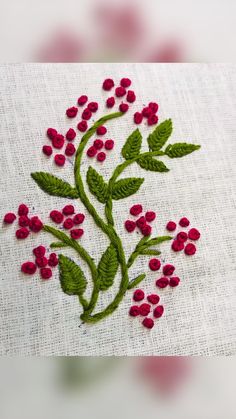 a close up of a piece of cloth with flowers and leaves embroidered on the side