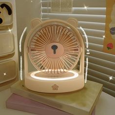 a small fan sitting on top of a table next to some books and other items