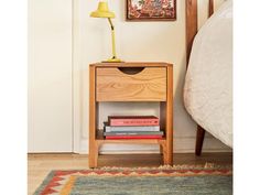 a nightstand with books on it next to a bed