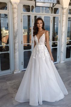 a woman standing in front of a building wearing a wedding dress