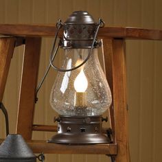 an old fashioned light hanging from a wooden ladder