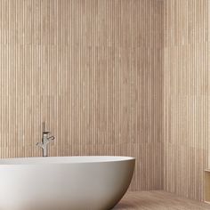 a white bath tub sitting on top of a wooden floor next to a wall mounted faucet