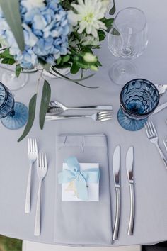 the table is set with silverware and blue flowers