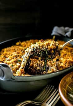 a casserole dish with spinach and cheese being lifted from the casserole