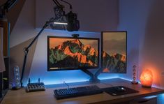 two computer monitors sitting on top of a wooden desk