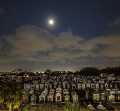 the moon shines brightly over a cemetery at night