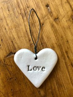 a ceramic heart ornament with the word love on it hanging from a cord