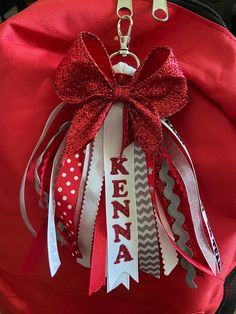 a red and white backpack with a bow on it's front pocket that says kenya