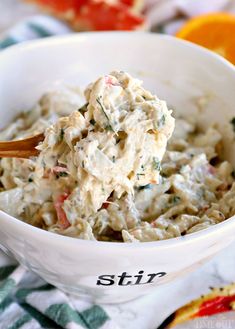 a white bowl filled with macaroni salad on top of a green and white checkered table cloth