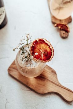 a grapefruit cocktail garnished with an orange slice on a wooden serving board