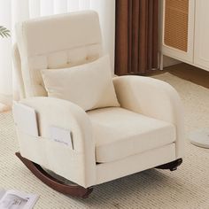 a white rocking chair sitting on top of a carpeted floor next to a window