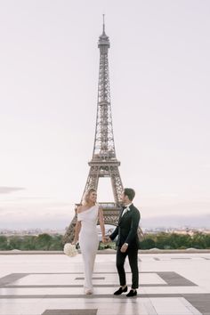 a bride and groom standing in front of the eiffel tower, paris france