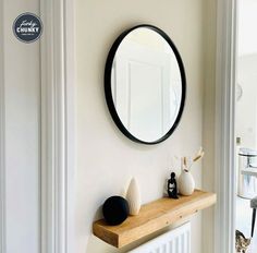 there is a mirror on the wall above a shelf with vases and other items