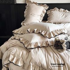 the bed is made with ruffled sheets and pillows