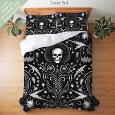 a black and white bed with a skull on the cover next to a potted plant