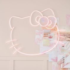 a pink hello kitty neon sign hanging from the side of a wall