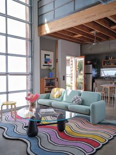 a living room filled with furniture and a glass table on top of a colorful rug