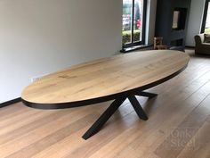 a large wooden table sitting on top of a hard wood floor next to a window