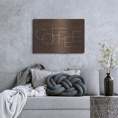 a living room with a gray couch and white pillows on top of it, next to a coffee sign