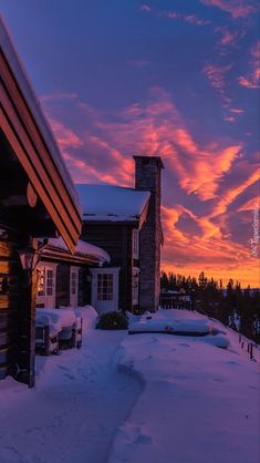 the sun is setting over some houses in the snow