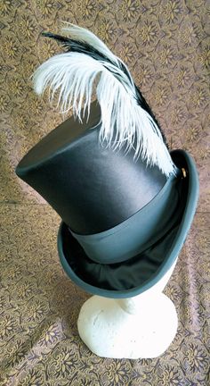 Reproduction of a female top hat of French production from around 1885. Dome 15 cm high in black satin and trimmings in dark gray satin crepe, 5 cm brim. 3 black and white ostrich feathers complete the decoration. Lined interior in burgundy satin, sweatband in soft black cotton grosgrain. On request it is also possible to make it in other colors Top Hat Veil, Top Hat With Feathers, Fancy Top Hat, Womens Top Hat, Ringleader Hat, Feminine Hats, Feather Tops, Style Français, Satin Noir