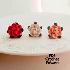 three crocheted flowers sitting on top of a white doily covered cake plate