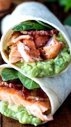 two wraps filled with meat and guacamole on top of a wooden table