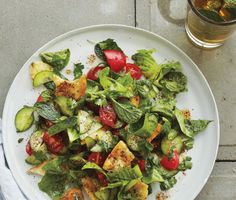 a white plate topped with lots of veggies next to a glass of beer