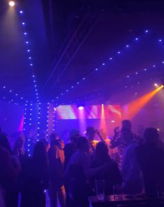 a group of people standing around in a room with lights on the walls and floor