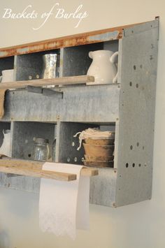 an old wooden shelf with some jars on it and toilet paper hanging from the wall