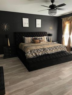 a bedroom with black walls and wood flooring has a chandelier above the bed